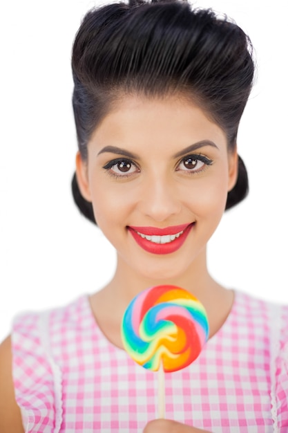 Modelo alegre del pelo negro que sostiene un lollipop coloreado