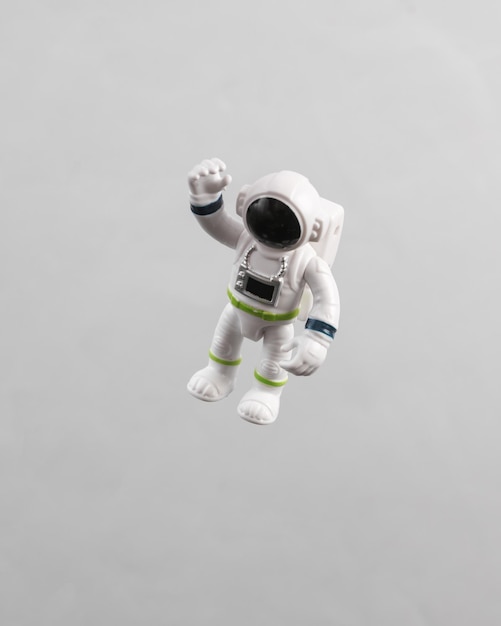 Modelo de astronauta de juguete volando en antigravedad sobre un fondo gris