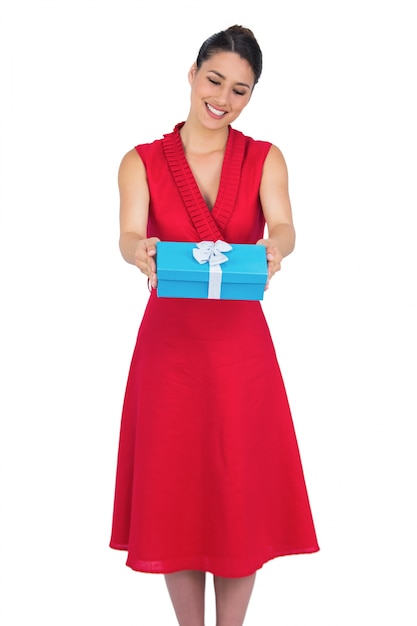 Foto modelo atractivo sonriente en vestido rojo que ofrece presente