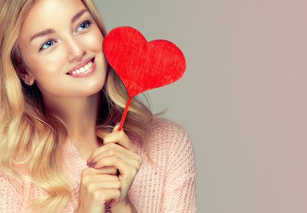 Foto el modelo atractivo sostiene un corazón simbólico en el palo.