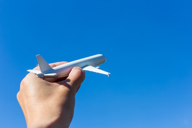 Modelo de avión en mano en el cielo soleado