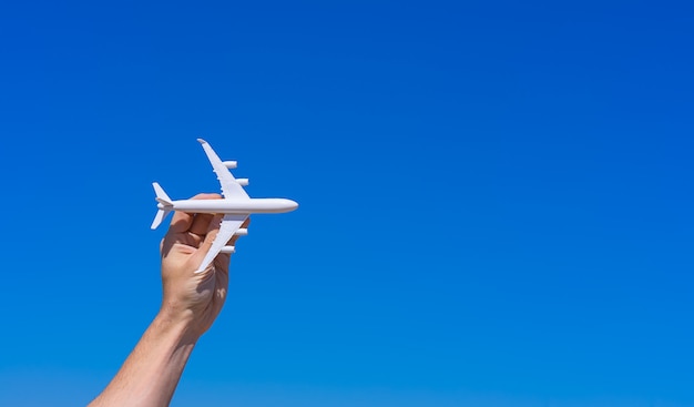 Modelo de avión en mano contra el cielo azul claro