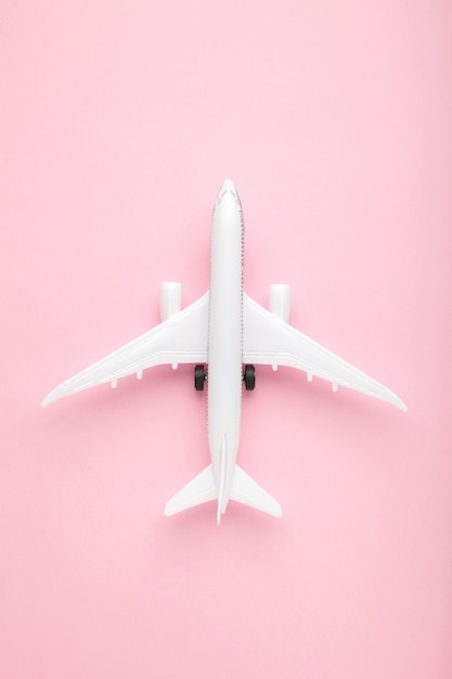 Modelo de avión en la pared de color rosa pastel. Concepto de viaje