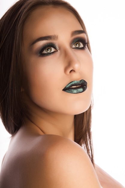 Modelo bastante joven con una piel perfecta y maquillaje verde metálico creativo. Retrato de primer plano en el estudio sobre un fondo blanco.