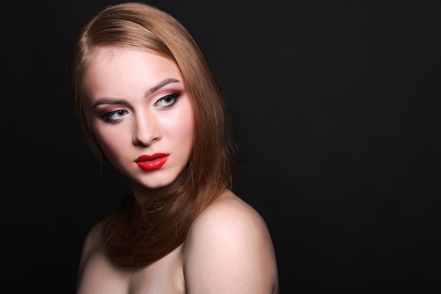 Modelo de belleza sobre fondo negro con espacio de copia, fotografía de moda. Mujer con maquillaje, piel perfecta y cabello posando para la cámara en el estudio