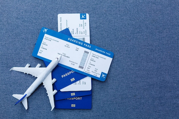 Modelo en blanco blanco de avión de pasajeros en pasaportes con tarjeta de embarque sobre fondo azul de madera rústica