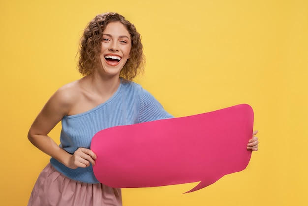 Modelo con bocadillo de diálogo rosa, sonriendo con dientes.