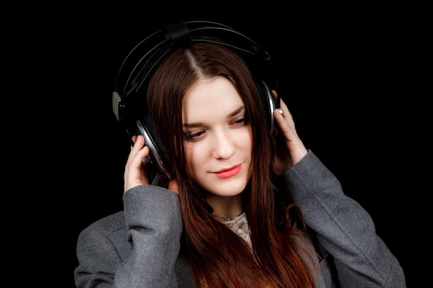 Modelo de cabello oscuro está posando en un estudio oscuro con auriculares en la cabeza