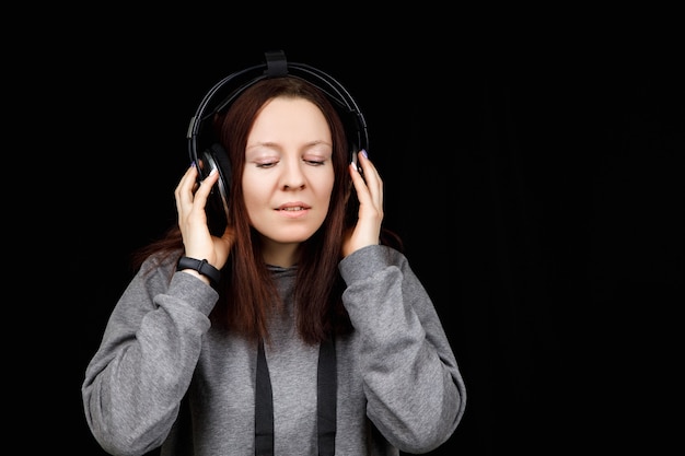 Modelo de cabello oscuro está posando en un estudio oscuro con auriculares en la cabeza