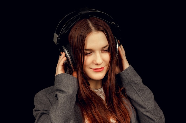 Modelo de cabello oscuro está posando en un estudio oscuro con auriculares en la cabeza