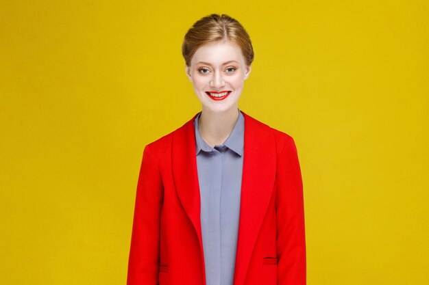 Modelo de cabeza roja de felicidad divertida en traje rojo sonrisa con dientes. Foto de estudio, aislado sobre fondo amarillo