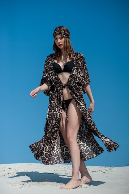 Una modelo camina por la playa con un kimono con estampado de leopardo.