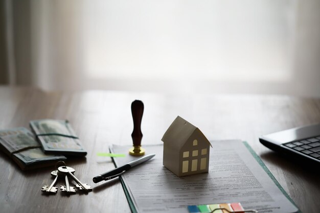 Modelo de casa con agente de bienes raíces y cliente discutiendo por contrato para comprar seguro de casa o fondo de préstamo de bienes raíces