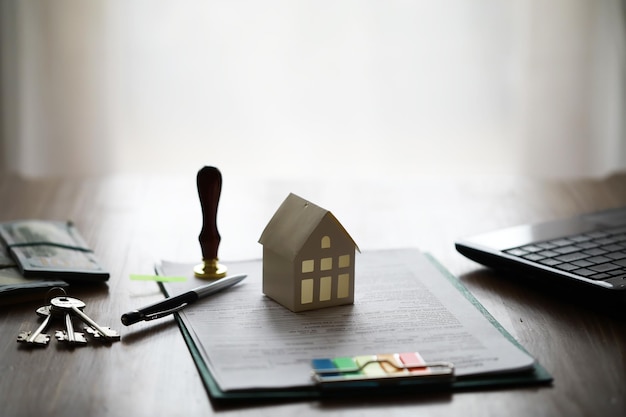 Modelo de casa con agente de bienes raíces y cliente discutiendo por contrato para comprar seguro de casa o fondo de préstamo de bienes raíces
