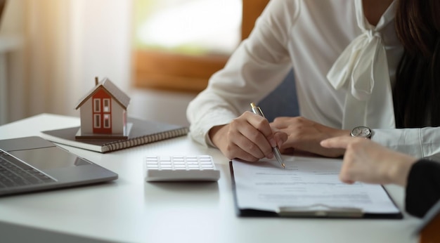 Modelo de casa con agente y cliente discutiendo por contrato para comprar obtener seguro o préstamo inmobiliario