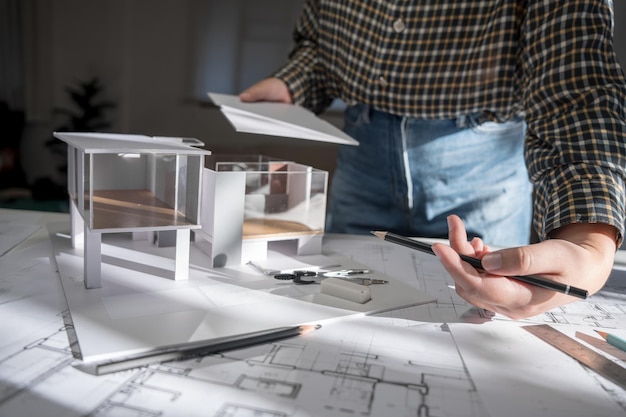 Modelo de casa en Buleprint dibujo de construcción y equipo de dibujo estacionario Arquitecto analizando modelo de casa casa moderna en la mano Arquitecto Diseño