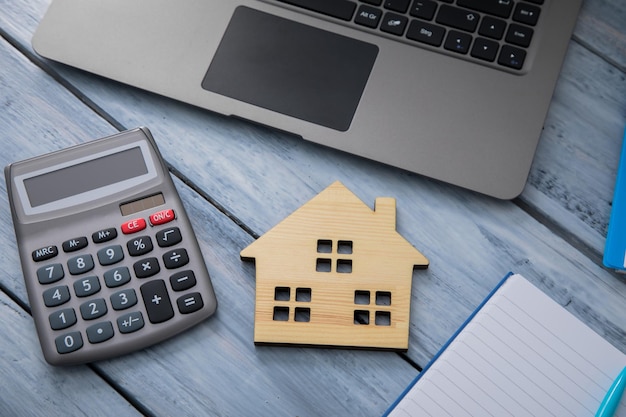 Foto modelo de casa con calculadora y cuaderno.