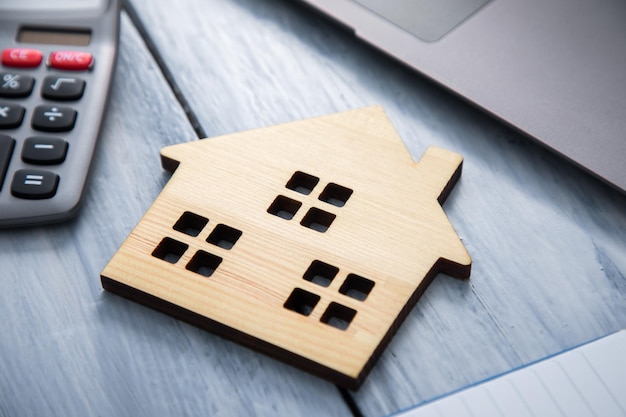 Modelo de casa con calculadora y cuaderno.