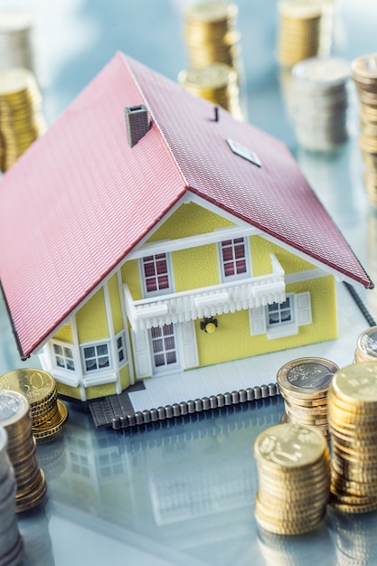 Foto modelo de casa familiar con monedas como concepto de banco o seguro.