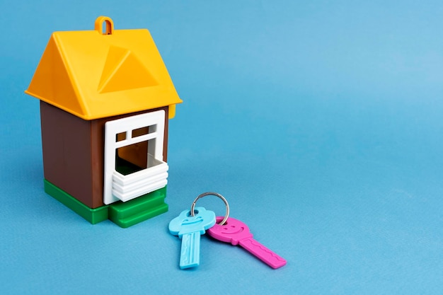Modelo de casa y llaves sobre un fondo azul Compra de bienes inmuebles