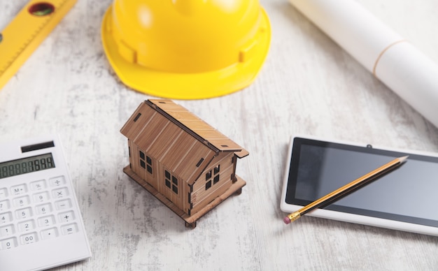 Modelo de casa de madera con casco y tableta.