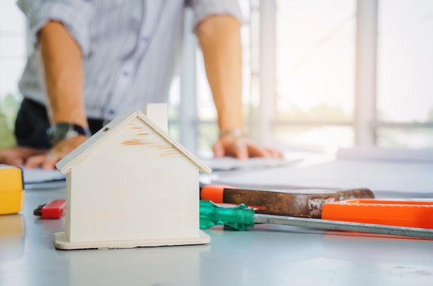 modelo de casa de madera y herramientas en la mesa con la planificación del ingeniero poner en marcha el nuevo proyecto