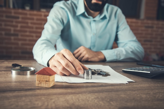 Modelo de casa de madera con monedas o concepto inmobiliario