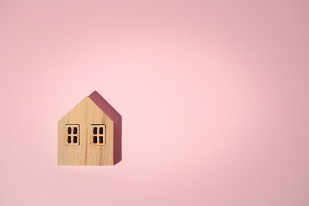 Modelo de casa de madera sobre fondo rosa con espacio de copia para el concepto de vivienda