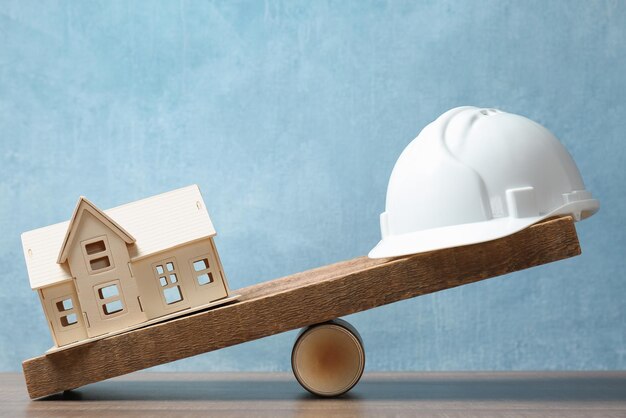 Foto modelo de casco de casa y constructor en escalas de madera concepto de equilibrio entre el trabajo y la vida personal