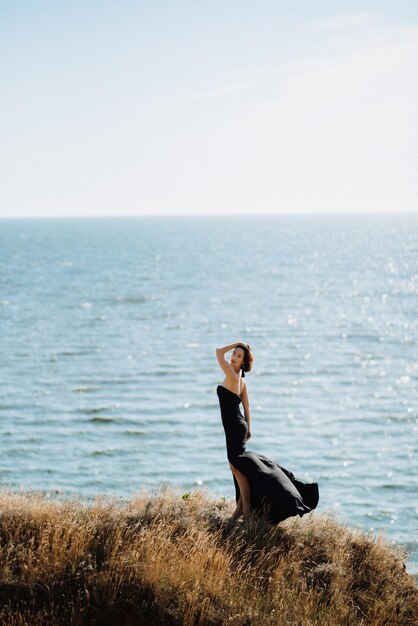 Modelo de chica alta con un vestido negro en las colinas de la montaña