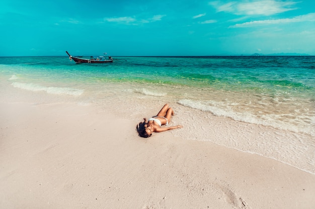 Modelo de chica joven y bonita en bikini tomando el sol en el balneario del mar de Andaman