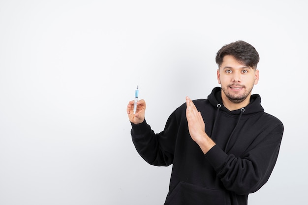 Modelo de chico guapo sosteniendo una jeringa de plástico con líquido para inyección