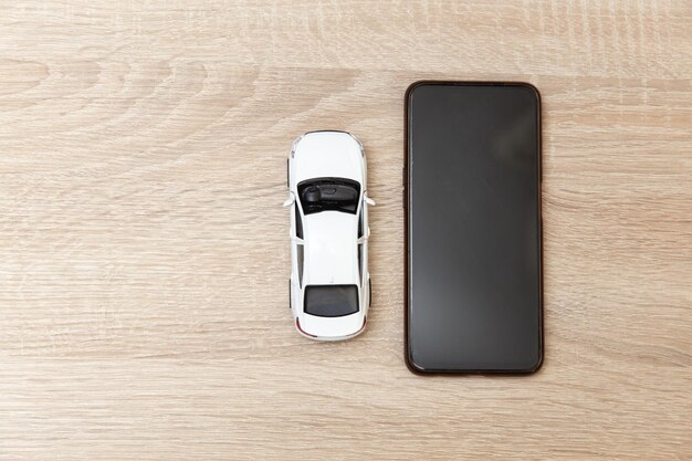 Modelo de coche de juguete con teléfono inteligente en una mesa de madera