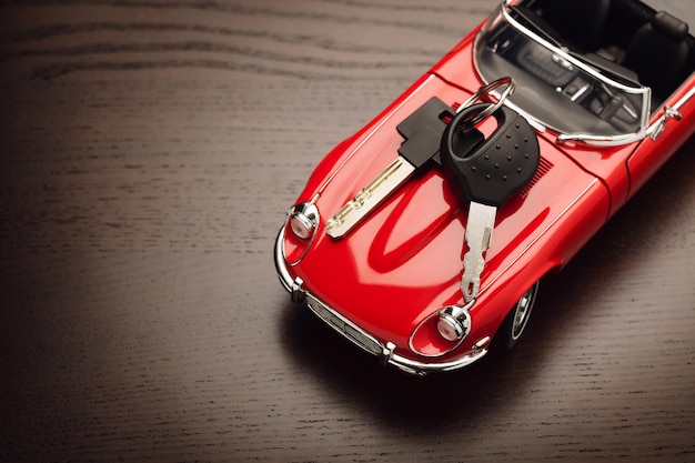 Modelo de un coche rojo con candado en la superficie de madera Concepto de compra o venta de un coche