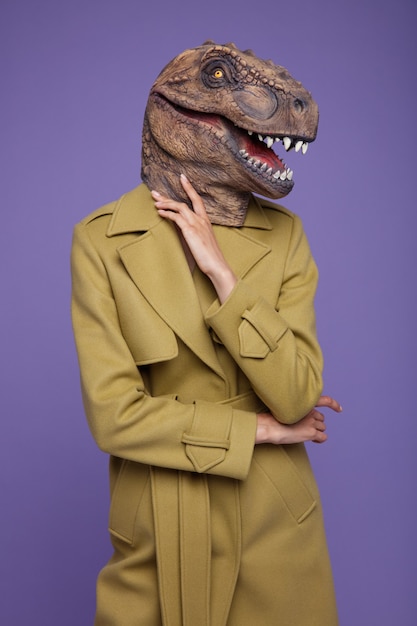 Modelo com capa de mostarda amarela tiranossauro rex máscara de dinossauro em um fundo roxo