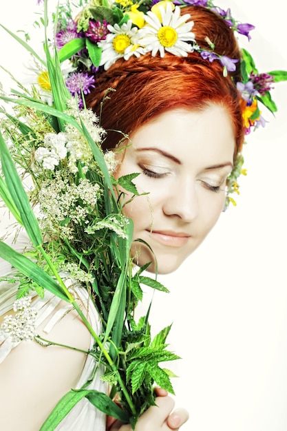 Modelo com grande penteado e flores no cabelo e com buquê de flores