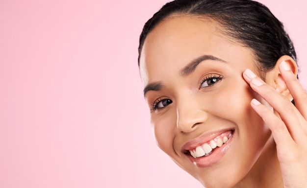 Modelo de cuidado de la piel belleza y retrato de la mujer en el estudio para el bienestar tratamiento facial y cosméticos spa de dermatología y persona femenina tocando la cara para la salud brillo y brillo en fondo rosa
