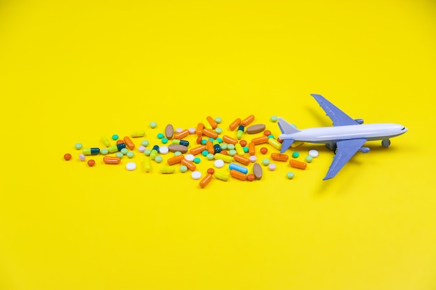 Modelo de avião com pílulas multicoloridas de close-up de enjoo em um fundo amarelo. conceito de doença em viagens. foco seletivo