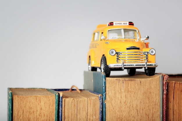 Modelo de brinquedo de ônibus escolar amarelo e livros antigos.