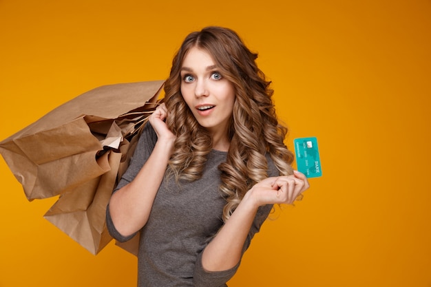 Modelo de cabelo bem encaracolado posando com sacolas e cartão de crédito