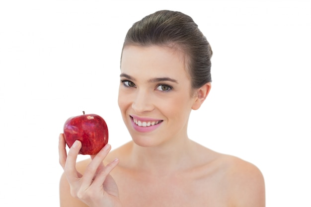 Modelo de cabelo castanho natural descontraído segurando uma maçã vermelha