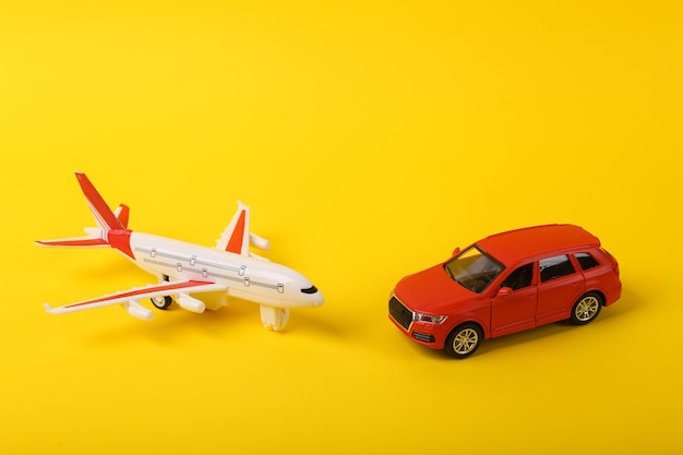 Foto modelo de carro de brinquedo com um avião em fundo amarelo conceito de viagem