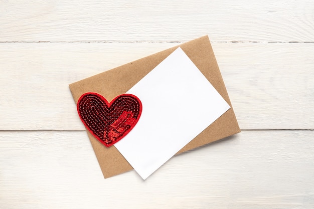 Modelo de cartão de felicitações com envelope de papel artesanal e corações vermelhos brilhantes