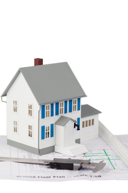 Modelo de casa de brinquedo e pinça em um plano de piso térreo