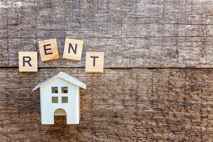 Foto modelo de casa de brinquedo em miniatura com inscrição rent letras palavra em fundo de madeira