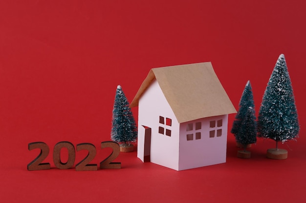 Modelo de casa e uma árvore de Natal em fundo vermelho 2022 ano novo