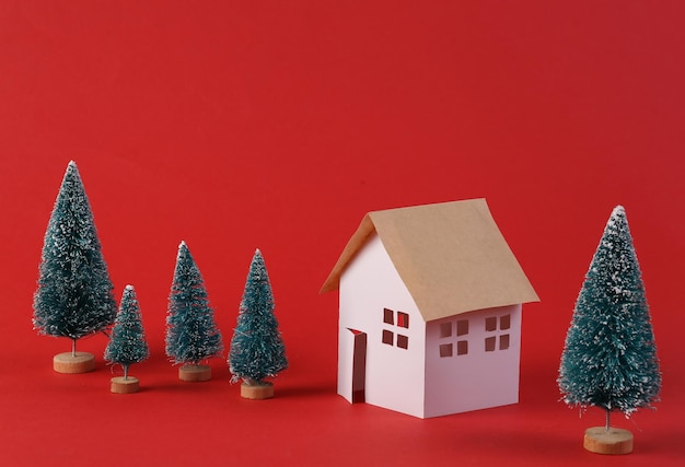 Modelo de casa e uma árvore de Natal em fundo vermelho