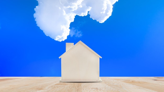 Modelo de casa pequena na mesa de madeira com fundo de céu azulVida familiar e conceito de negócios imobiliários