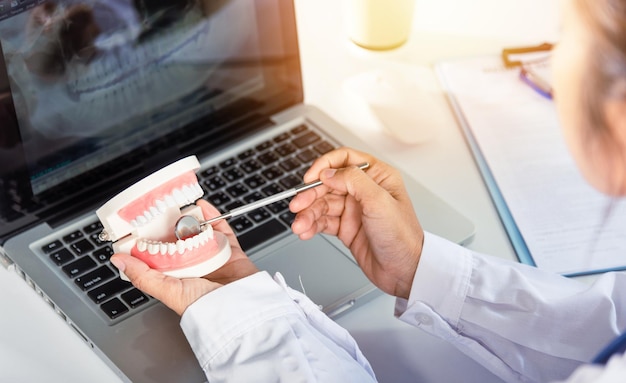 Modelo de dente branco saudável de dentista e instrumento de ferramenta de espelho explorador no dentista explicando ao paciente