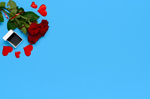 Modelo de dia de São Valentim. Vista superior, buquê de rosas vermelhas, corações e caixa para anel em fundo vermelho